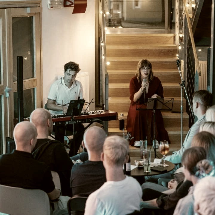 Piano and voice performance for a seated audience at a private gathering