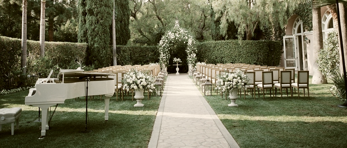 Garden wedding ceremony set with a white grand piano beside the aisle